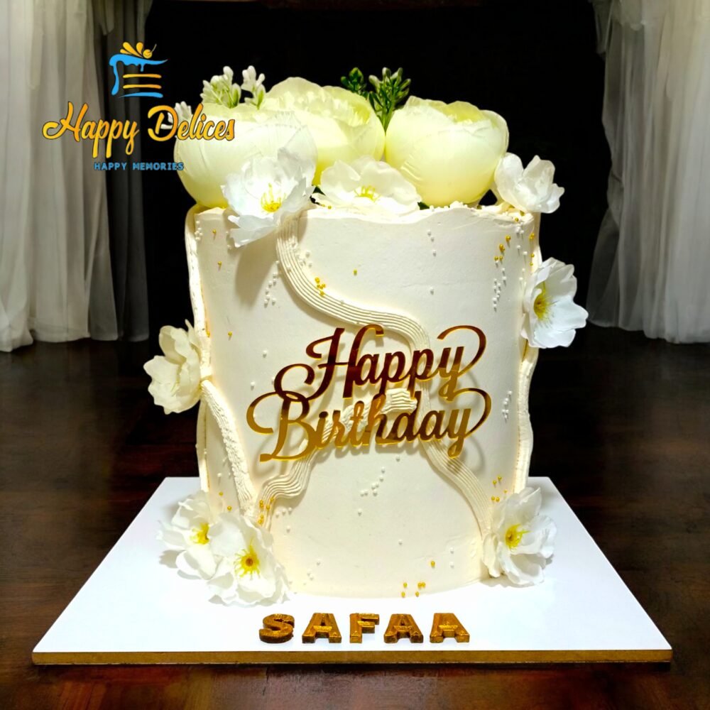 White birthday cake with delicate flowers and golden details, elegant design