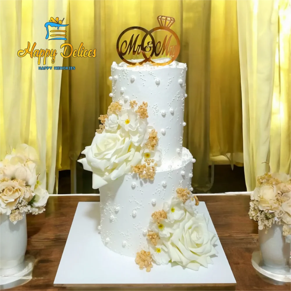 Two-tier white wedding cake with white and golden flowers, elegant design