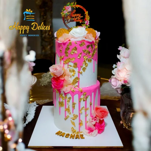 Two-tier pink and gold drip birthday cake with flowers and elegant design