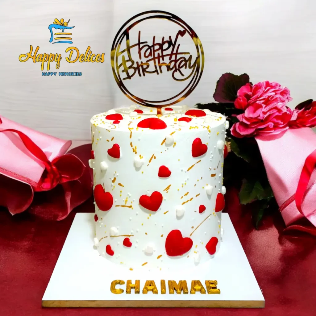 White birthday cake with red hearts and golden details