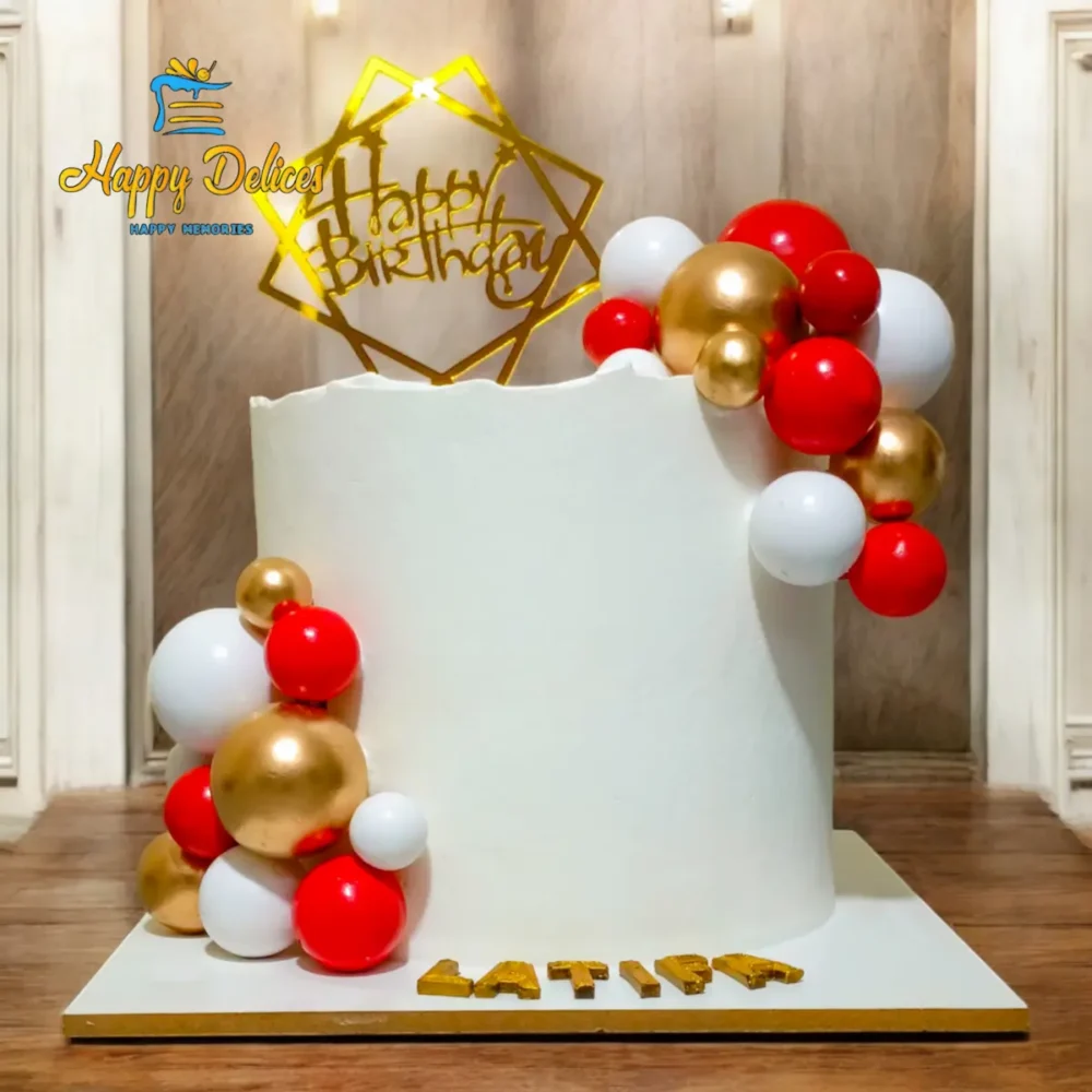 Minimal elegant birthday cake with white frosting, gold and red spheres, and modern topper