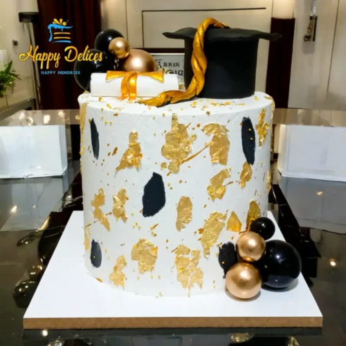 Elegant graduation cake with gold leaf, black details, and graduation cap decoration