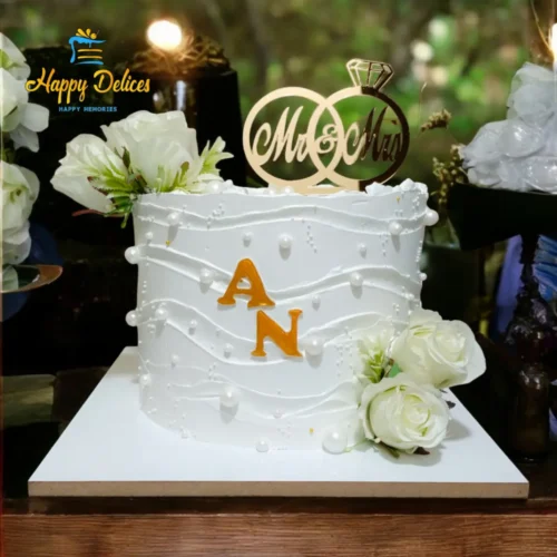 Elegant white engagement cake decorated with flowing pearl details and fresh white roses.