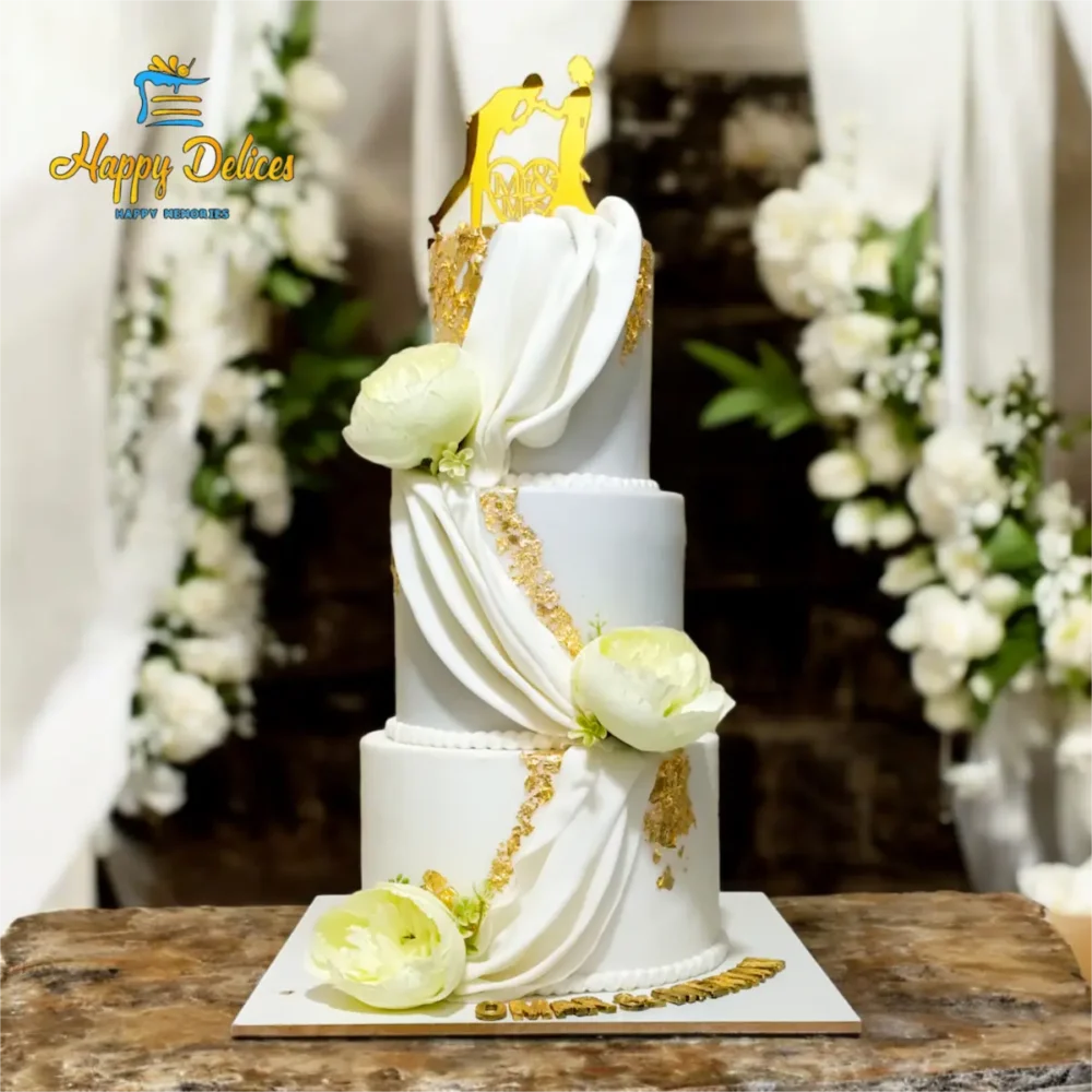 Elegant White & Gold Wedding Cake | Happy Delices Elegant white and gold wedding cake decorated with draped fondant and white flowers